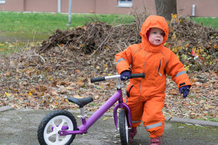 秋日，穿着暖和的衣服，骑着平衡自行车的孩子