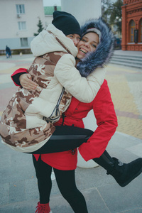 两个女孩在散步，在寒冷的天气结识朋友，女人穿着温暖的夹克热身，女性友谊的概念。