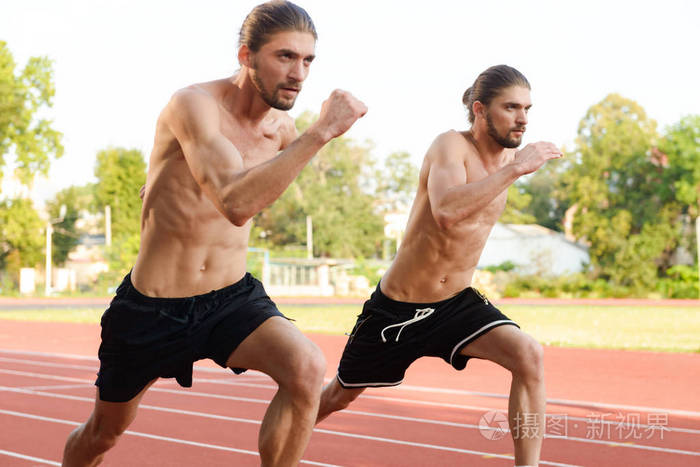 年轻的两对双胞胎运动员兄弟在户外体育场跑步的形象。
