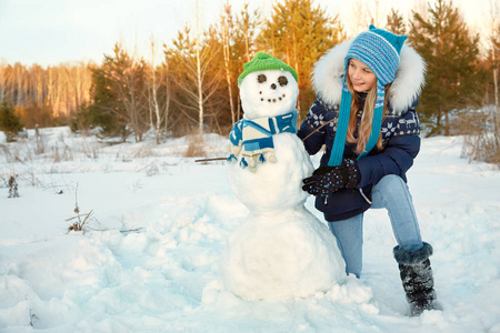 快乐的孩子玩雪人。 冬天户外散步的有趣女孩