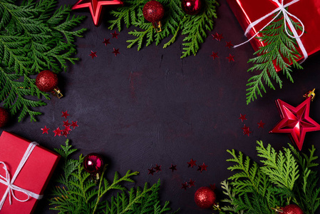 圣诞框架的红色礼品盒，冷杉树枝，纸屑和玩具在黑色背景。 平躺着。 上面的风景。 复制空间