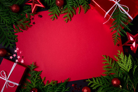 圣诞框架的红色礼品盒，冷杉枝纸屑纸，文字和玩具在黑色背景。 平躺着。 上面的风景。 复制空间