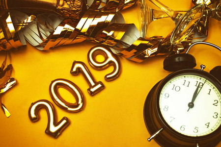 新年概念。 号码2019与时钟和黄金派对配件在黄色背景。