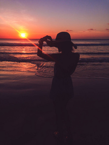 微笑的女孩在日落时欣赏海洋海景。
