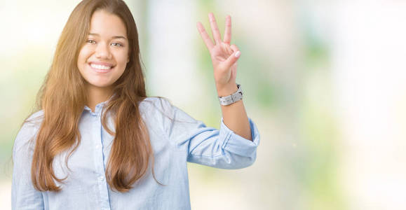 年轻漂亮的黑发商务女性，在孤立的背景下，展示和举着三个手指，同时微笑，自信和快乐。