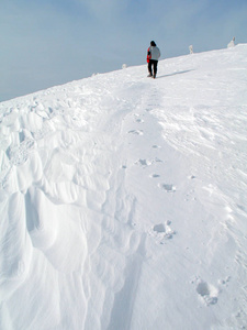 一个人穿过雪到山顶。 雪中的脚印链