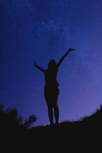一个女孩的轮廓,晚上双手在空中. 我的天文学工作.照片