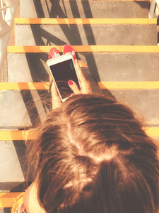 女性在城市环境中坐在楼梯上使用手机智能手机。