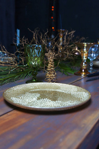 新年假期用金盘装饰桌子。 老式酒杯在老式的蓝色桌子上，上面有圣诞树。