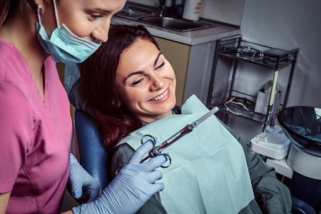 妇女患者坐在牙医椅子上, 而她的医生准备注射器注射照片