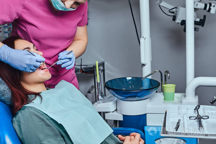 牙医正在治疗坐在诊所牙科椅上的女性病人