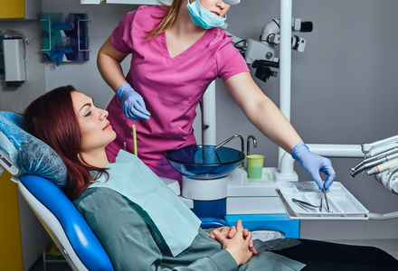 一名年轻的红发女子坐在诊所的牙科椅上接受检查