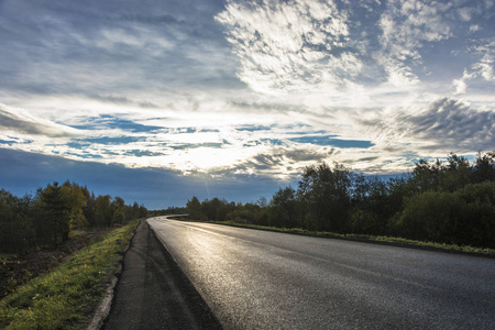 沥青路在明亮的背阳光下，在俄罗斯的清晨多云。