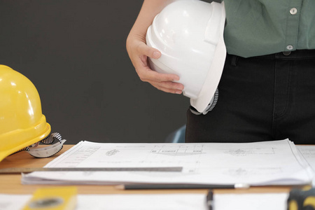 工程师，建筑师，工人，戴着安全帽，在工作场所的办公桌上绘制施工蓝图