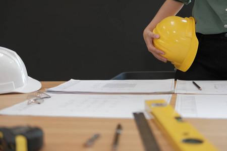 工程师，建筑师，工人，戴着安全帽，在工作场所的办公桌上绘制施工蓝图