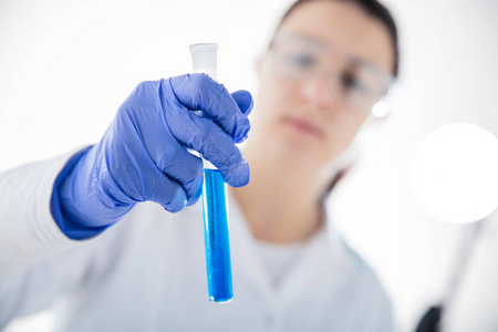 s hand on white background  holding test tube with blue liquid. 