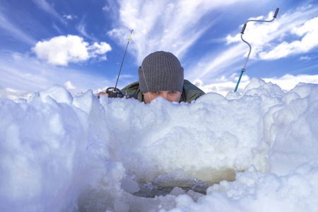冬季捕鱼的概念。 渔夫在行动。 人类正在从雪冰中躲藏和捕捉鱼。