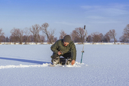 渔夫在行动. 从雪冰上抓鱼.照片