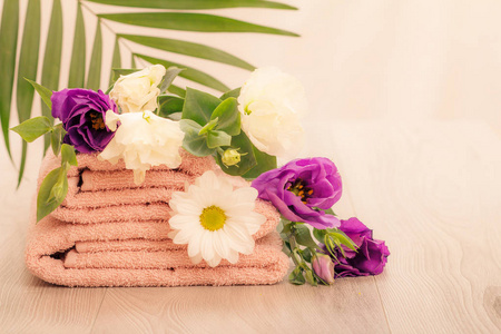 一叠柔软的特里毛巾，白色和紫色的花和粉红色背景上的绿叶。