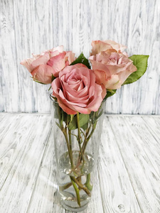 一束奶油糊状玫瑰放在木制背景上的玻璃花瓶里. 在花店工作照片
