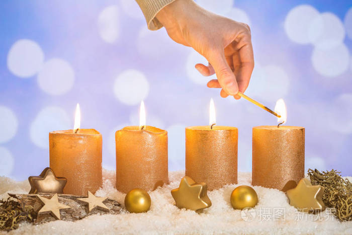四支金制蜡烛四支蜡烛用手点燃火柴和圣诞装饰放在雪地上作为模板