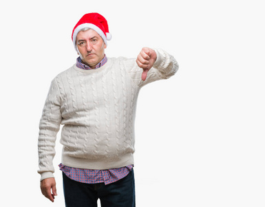 英俊的老人戴着圣诞帽，在孤立的背景上看起来不高兴和愤怒，表现出拒绝和消极的拇指向下的手势。 不好的表情。