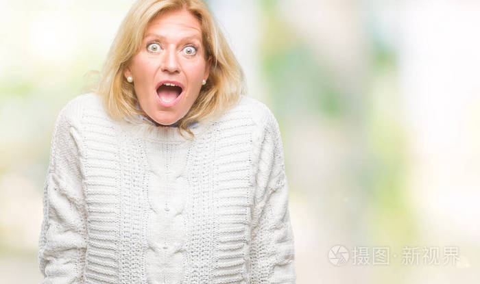 中年金发女人穿着冬季毛衣在孤立的背景下害怕和震惊惊讶的表情恐惧和