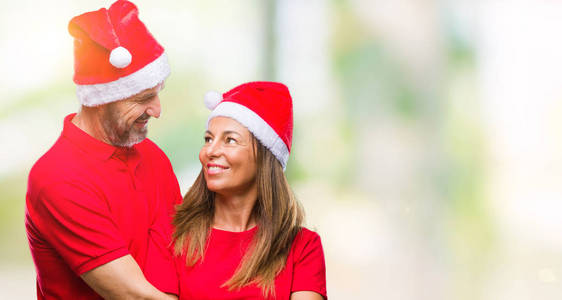 中年西班牙裔夫妇戴着圣诞帽，背景偏僻，脸上表情严肃。 简单自然地看着相机。