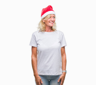 中年金发女人戴着圣诞帽，在孤立的背景下，面露微笑，表情自然。充满自信的笑。