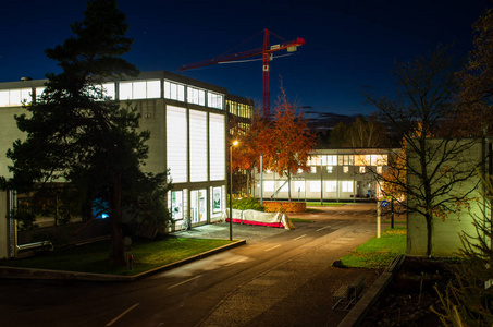 夜幕降临，蓝小时的城市景象照亮了背景大学校园里的建筑起重机