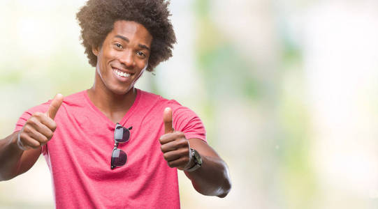 美国黑人男子在孤立的背景下赞成用手做积极的手势,竖起大拇指微笑,为