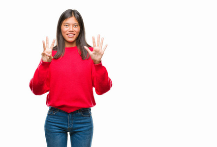 年轻的亚洲女人穿着冬天的毛衣，在孤立的背景上，用8号手指，微笑着自信和快乐。