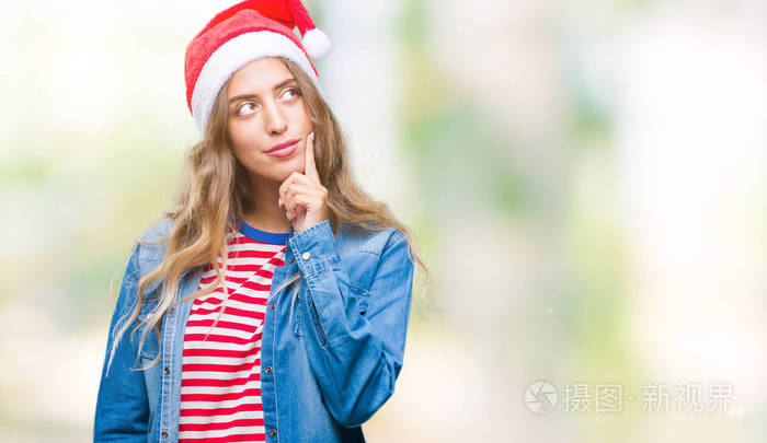 美丽的金发女郎戴着圣诞帽，戴着孤立的背景，手拿下巴思考问题，表情忧郁。带着若有所思的脸笑..怀疑的概念。