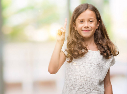 黑发西班牙女孩显示和指向第一手指，同时微笑自信和快乐。