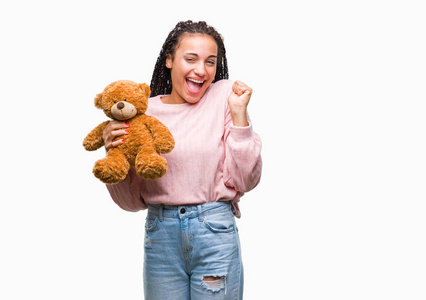 年轻的非裔美国女孩抱着玩具熊在孤立的背景下尖叫，自豪和庆祝胜利，非常兴奋，欢呼的情绪