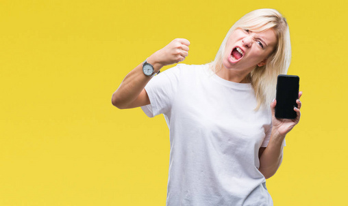 年轻漂亮的金发女郎在孤立的背景上展示智能手机屏幕,愤怒和沮丧,疯狂