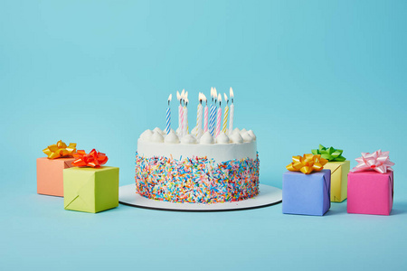 美味的蛋糕，蜡烛，五颜六色的礼物，蓝色背景的纸屑