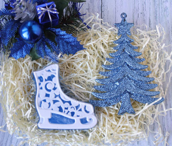 手工肥皂的形状冰鞋和蓝色圣诞装饰在一个轻的背景。 圣诞球礼物和针叶树枝。 圣诞快乐，新年快乐