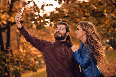 年轻夫妇在秋色公园用手机。