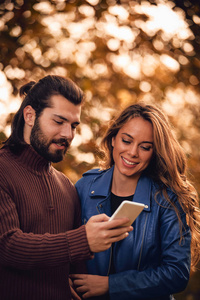 年轻夫妇在秋色公园用手机。