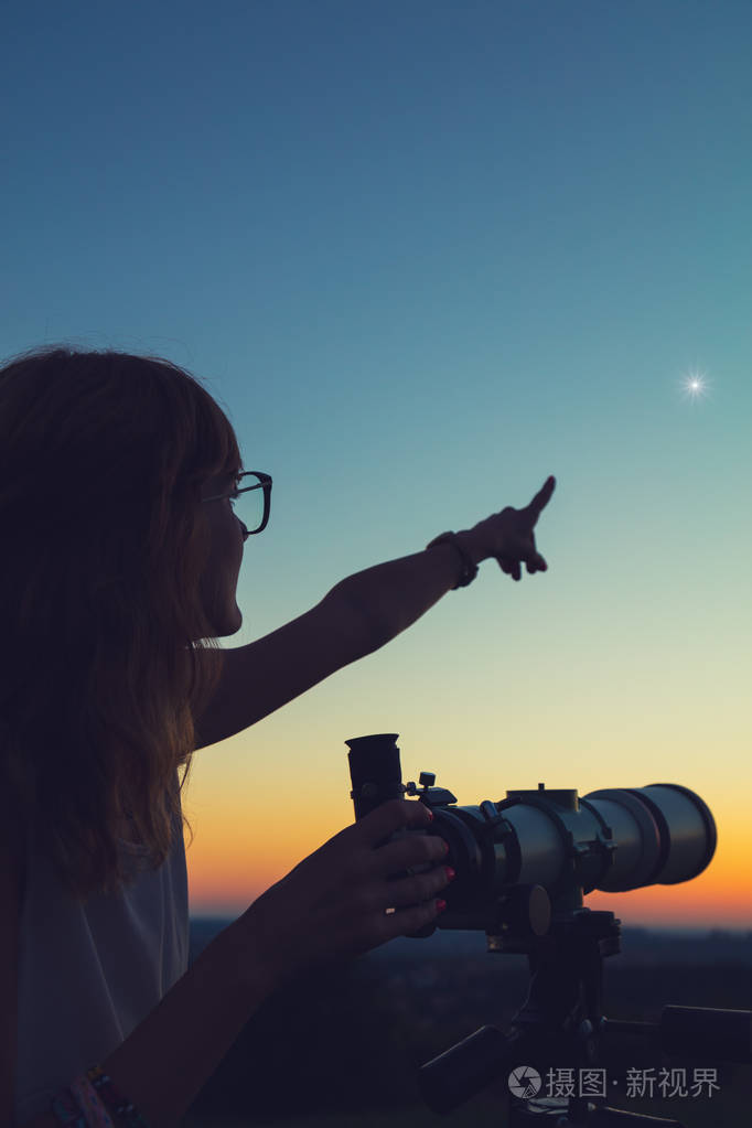 年轻的女人拿着天文望远镜看着天空