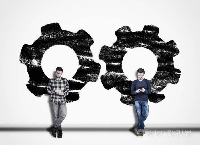 两个人用手机对着一堵白色的墙上面画着发动机齿轮机构共同工作的概念