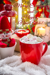 圣诞节装饰。 一个带有热可可棉花糖和蜡烛的杯子，赠送一条舒适的蓬松毯子。 圣诞节在家的和平和舒适的概念。 冬季背景的新年卡