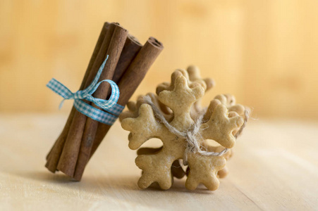 传统美味的捷克姜饼与黄麻绳，新鲜肉桂，蓝色蝴蝶结，圣诞雪花和香料在木桌上。