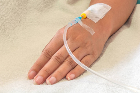 s hand with medicine drip injection, lady on a bed in a hospital