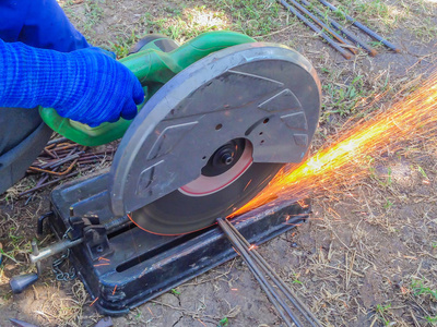 s hand cutting steel rod by a machine in construction site