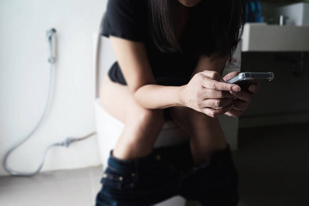 问题的概念女人坐在马桶上拿着纸巾健康问题的概念亚洲女孩坐在马桶上