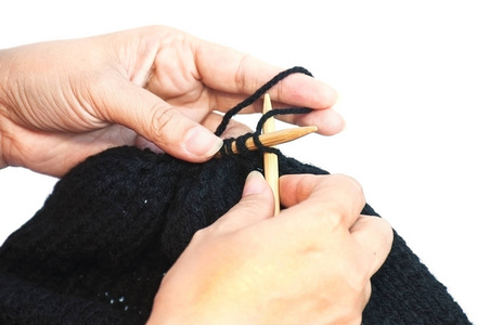 女人的手在做黑色帽子编织图片
