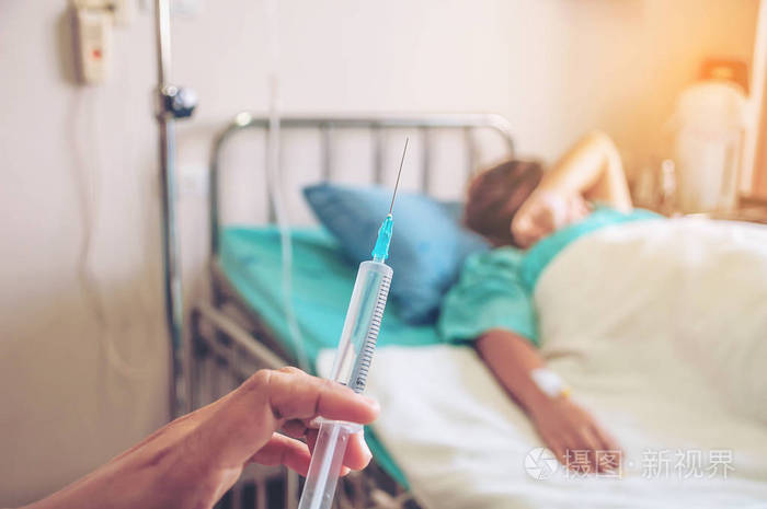 医生手里拿着注射器,准备在医院注射病人的背景
