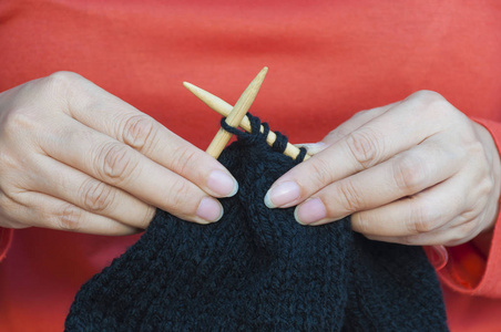 女人的手在做黑色帽子编织图片